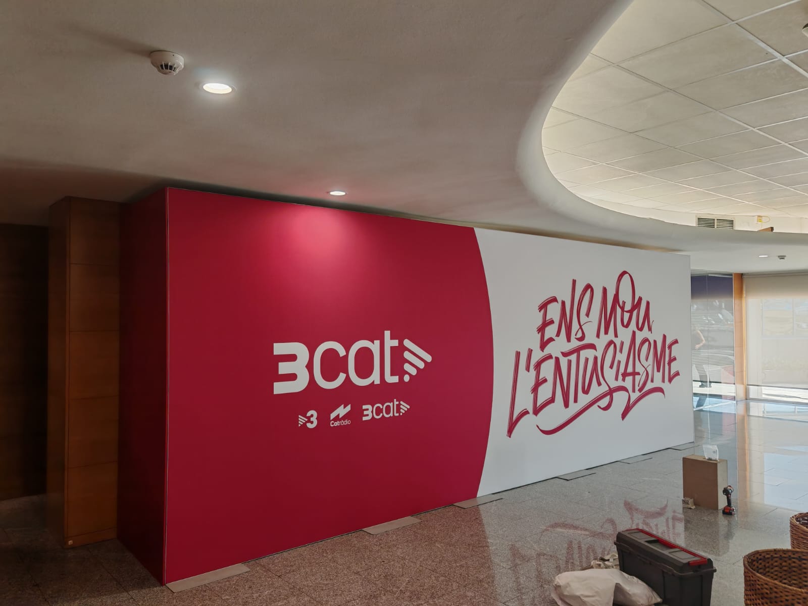 Vista lateral del mural 3cat mostrando el volumen y profundidad de la instalación en el hall