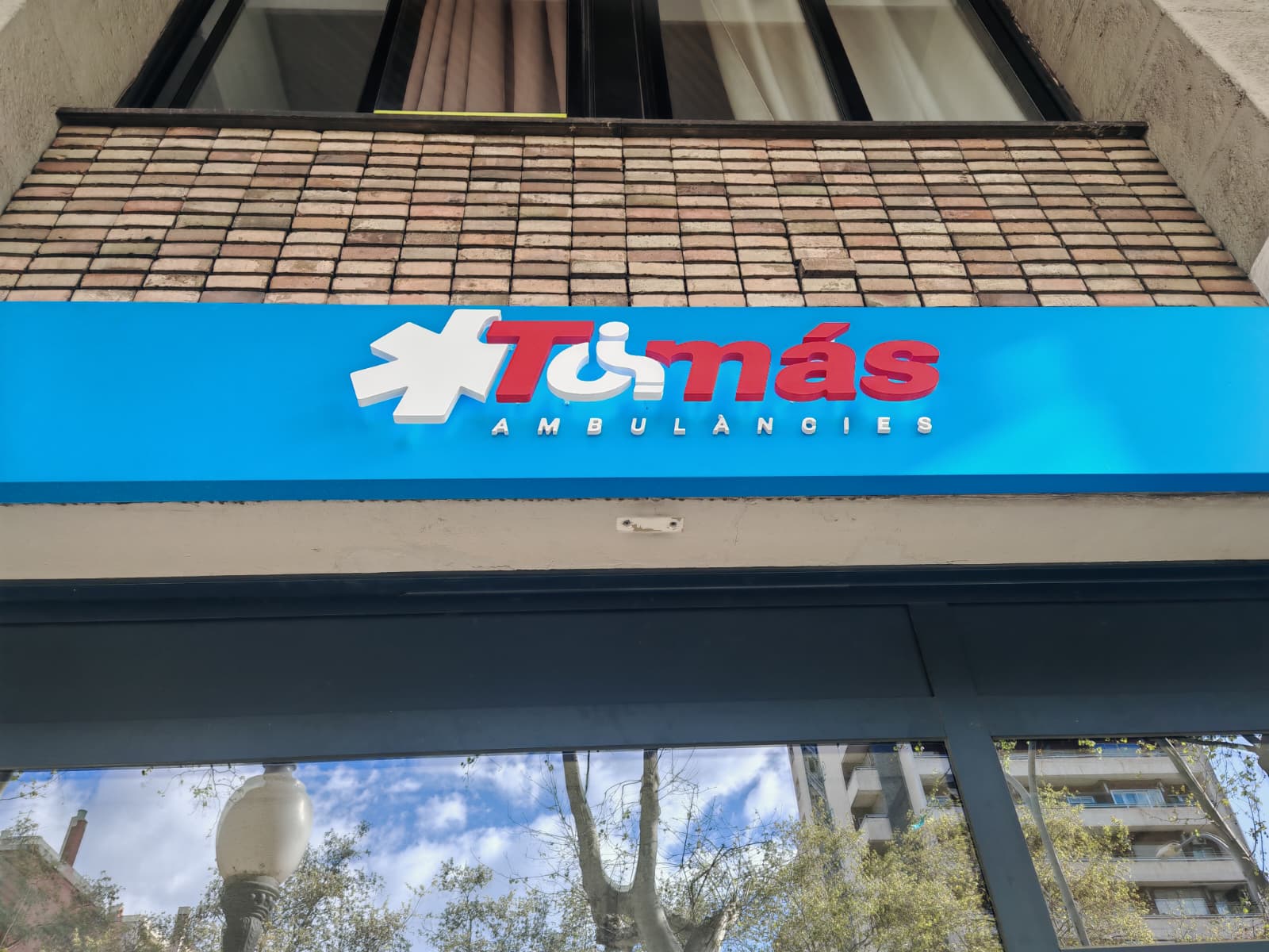 Vista general del rótulo Ambulàncies Tomàs en fachada con marquesina azul retroiluminada