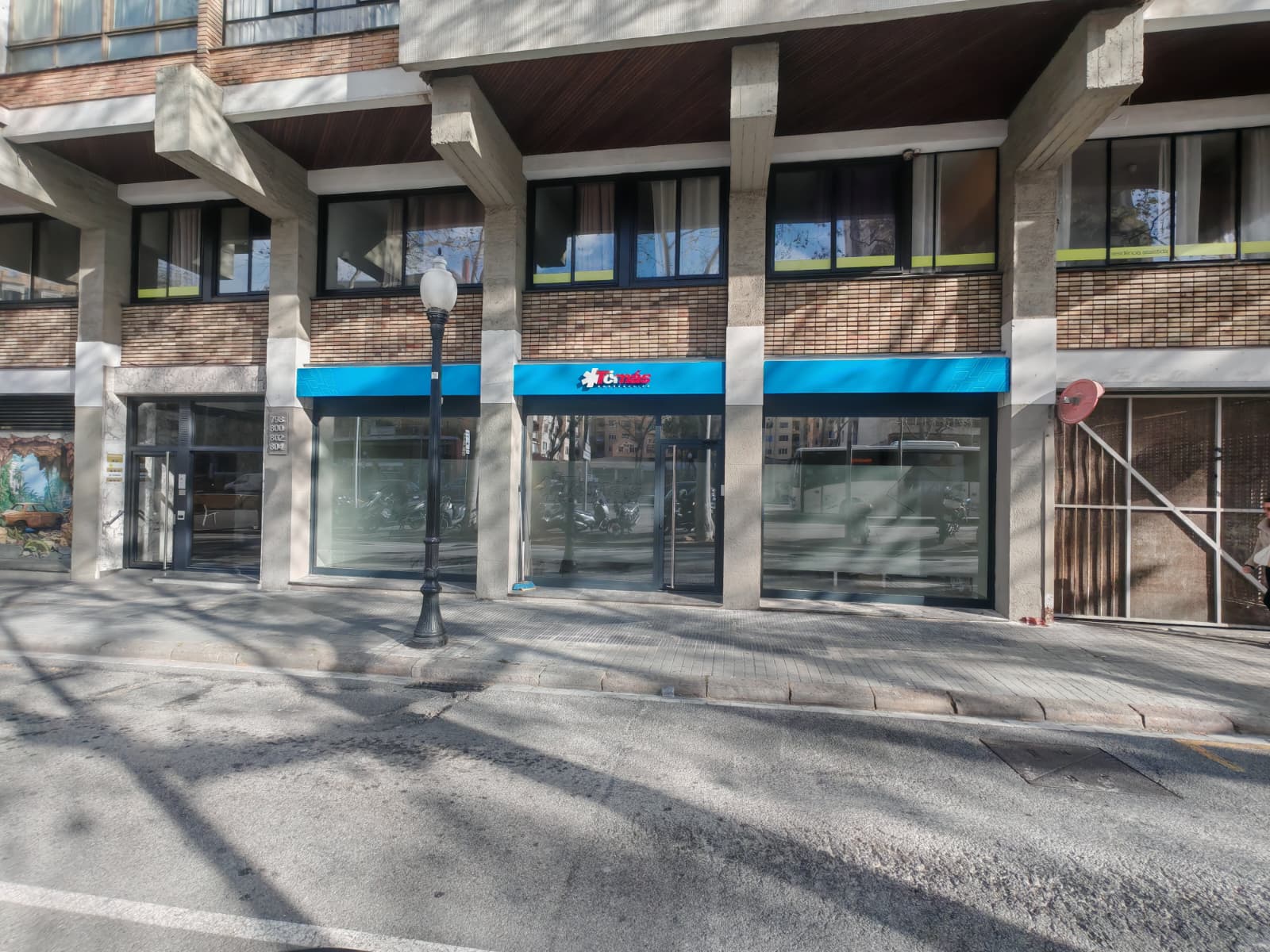 Vista completa de la fachada con marquesina azul corrida y rótulo Ambulàncies Tomàs