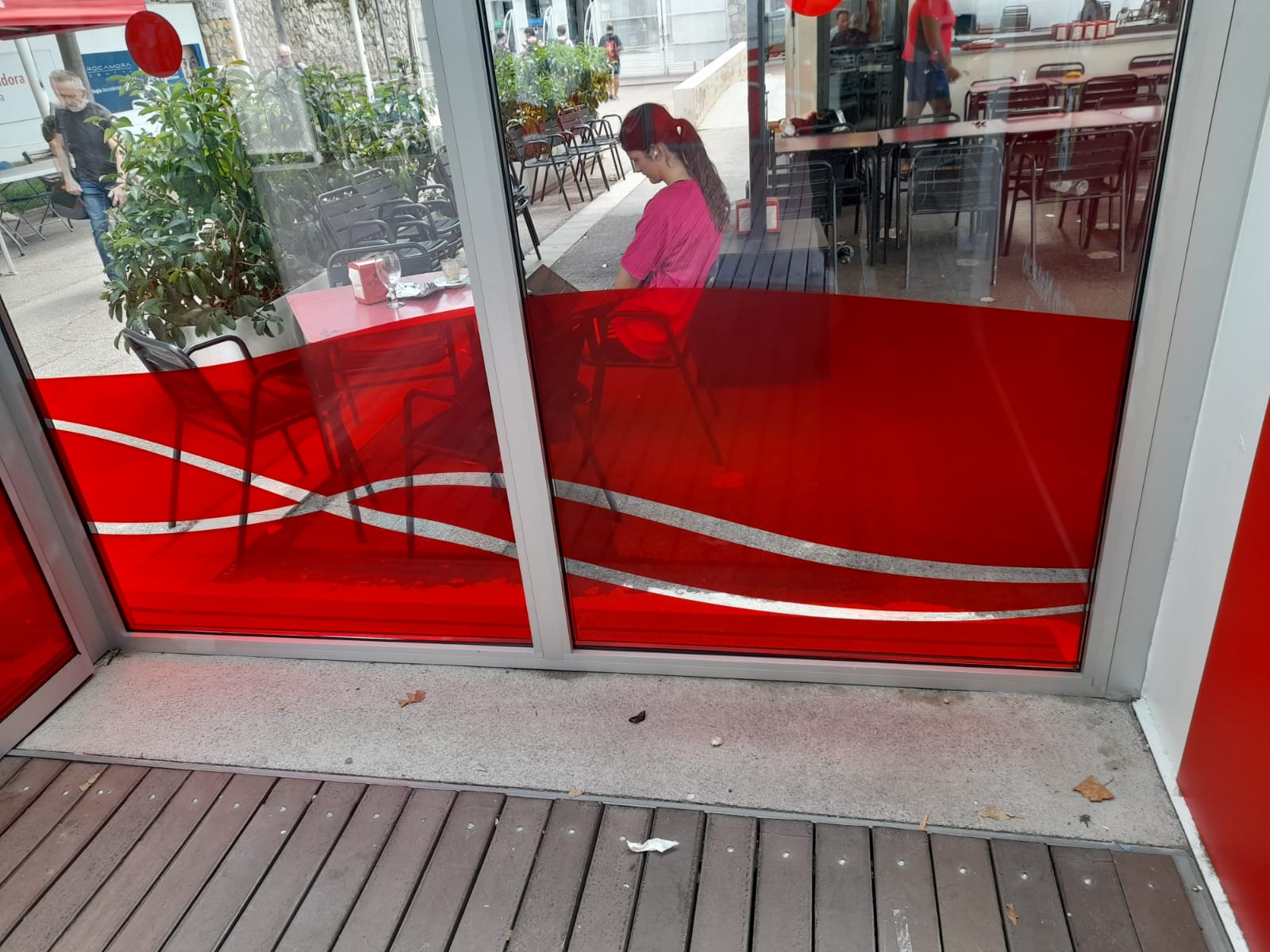 Detalle del vinilado en rojo con ondas blancas en puertas de cristal del CTN