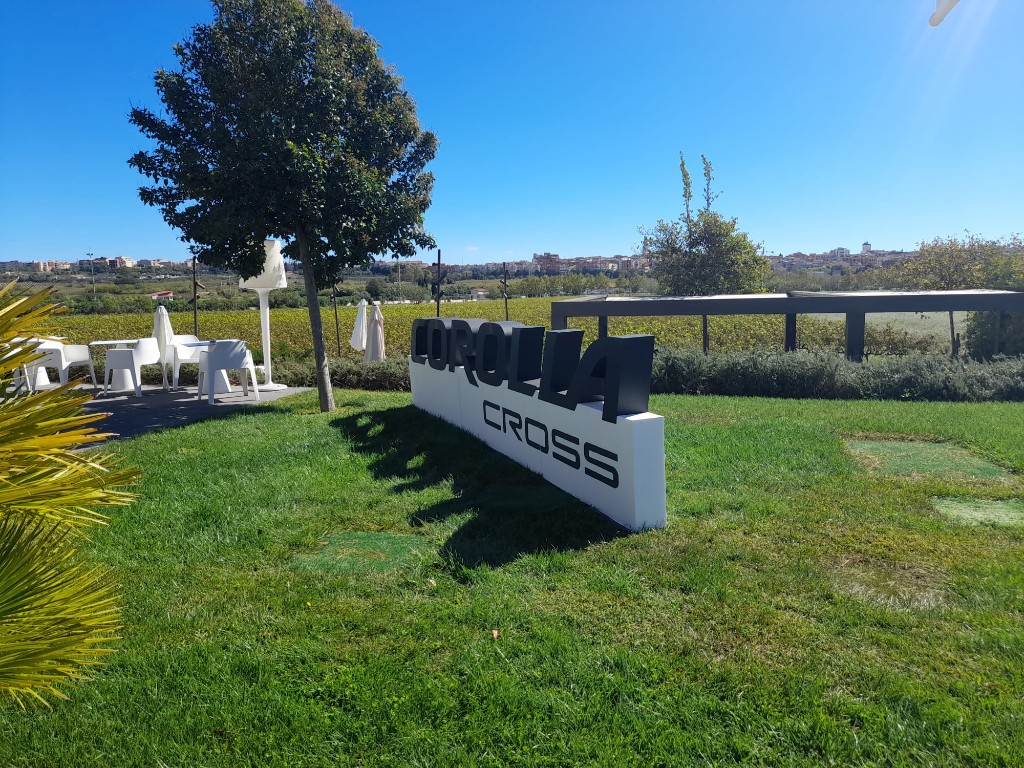 Vista lateral de instalación corpórea Corolla Cross sobre césped en evento