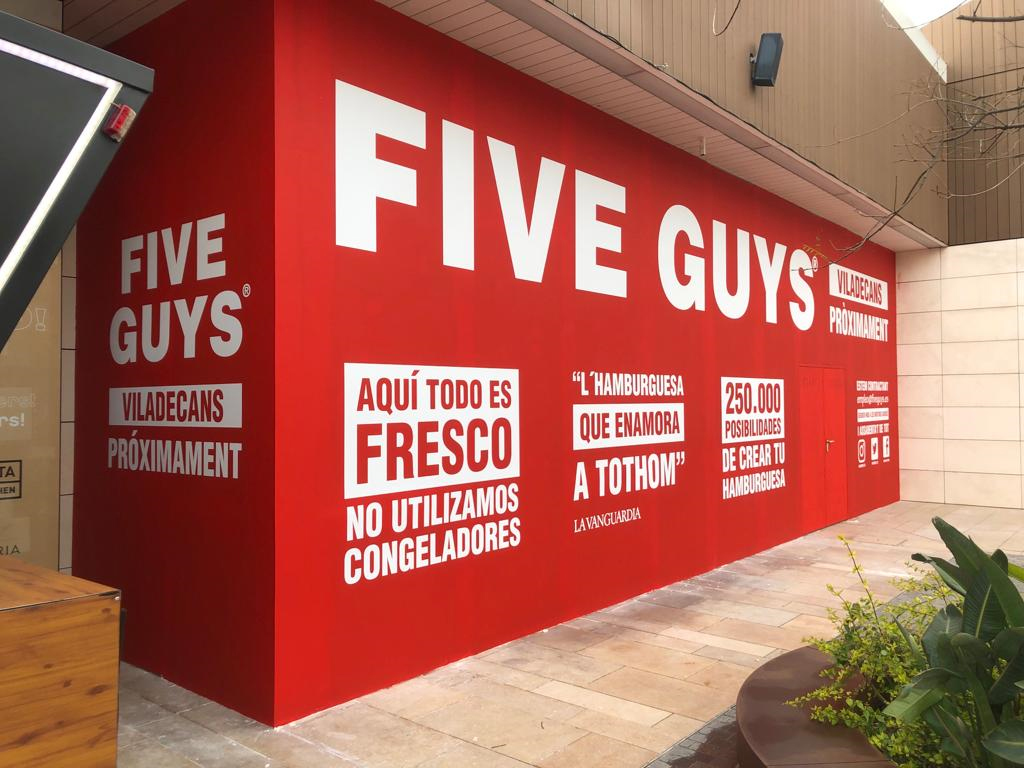 Cerramiento Five Guys Viladecans vista angular con claims de marca y redes sociales