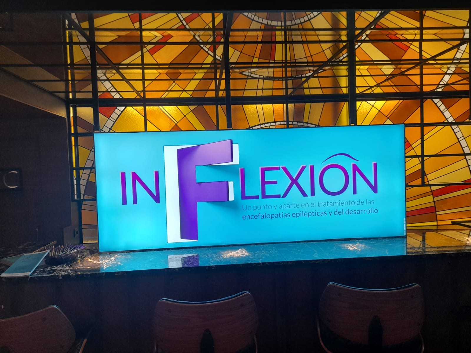 Caja de luz retroiluminada INFLEXION con logotipo en colores teal y morado corporativo