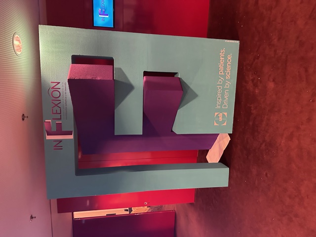 Pieza volumétrica 3D INFLEXION UCB con estructura en verde azulado y letras en relieve para evento farmacéutico