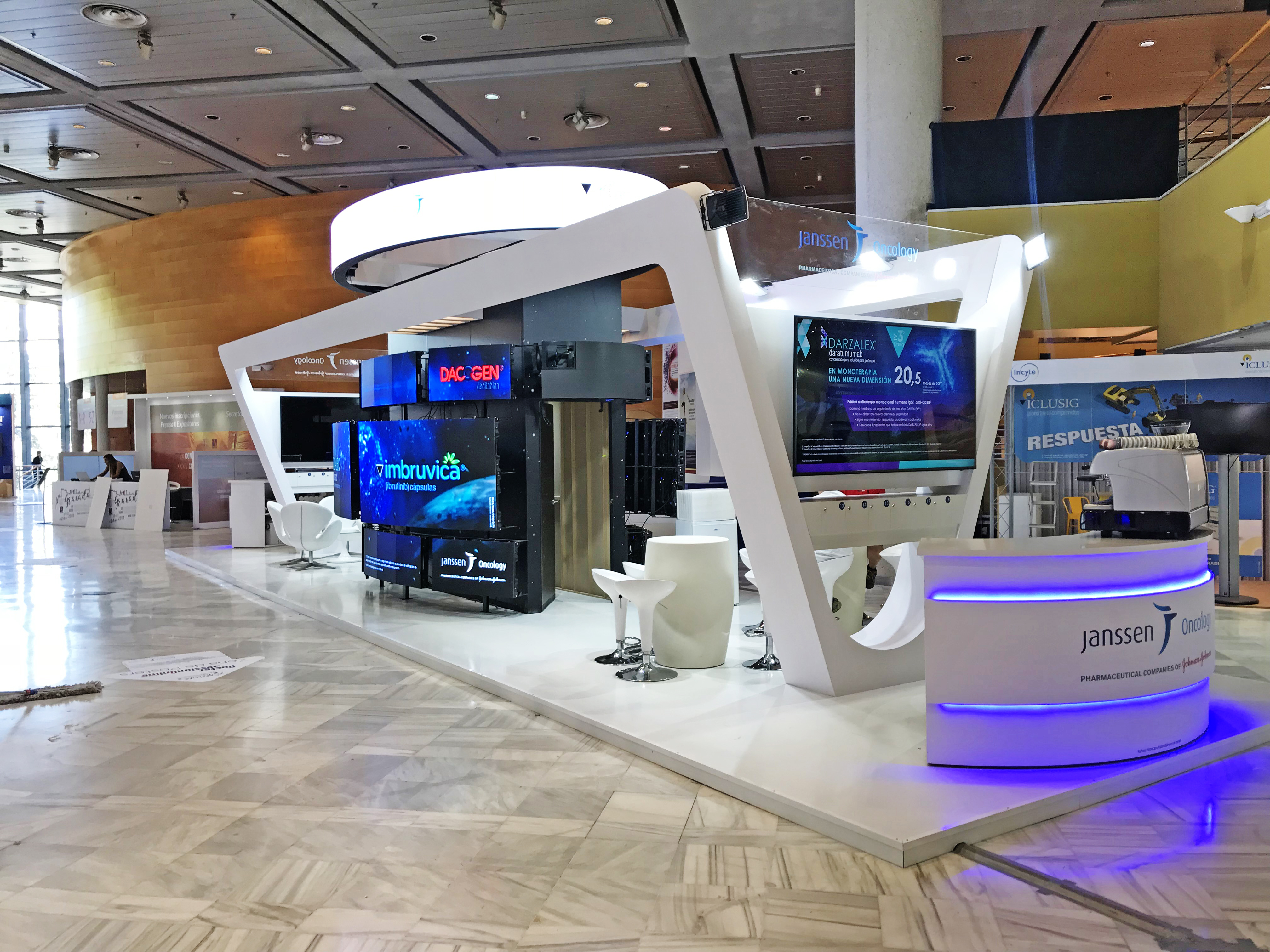 Stand Janssen Oncology con arco blanco angular y videowalls en congreso farmacéutico internacional