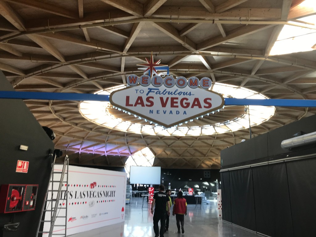 Vista general de sala de evento con rótulo Las Vegas suspendido e iluminado