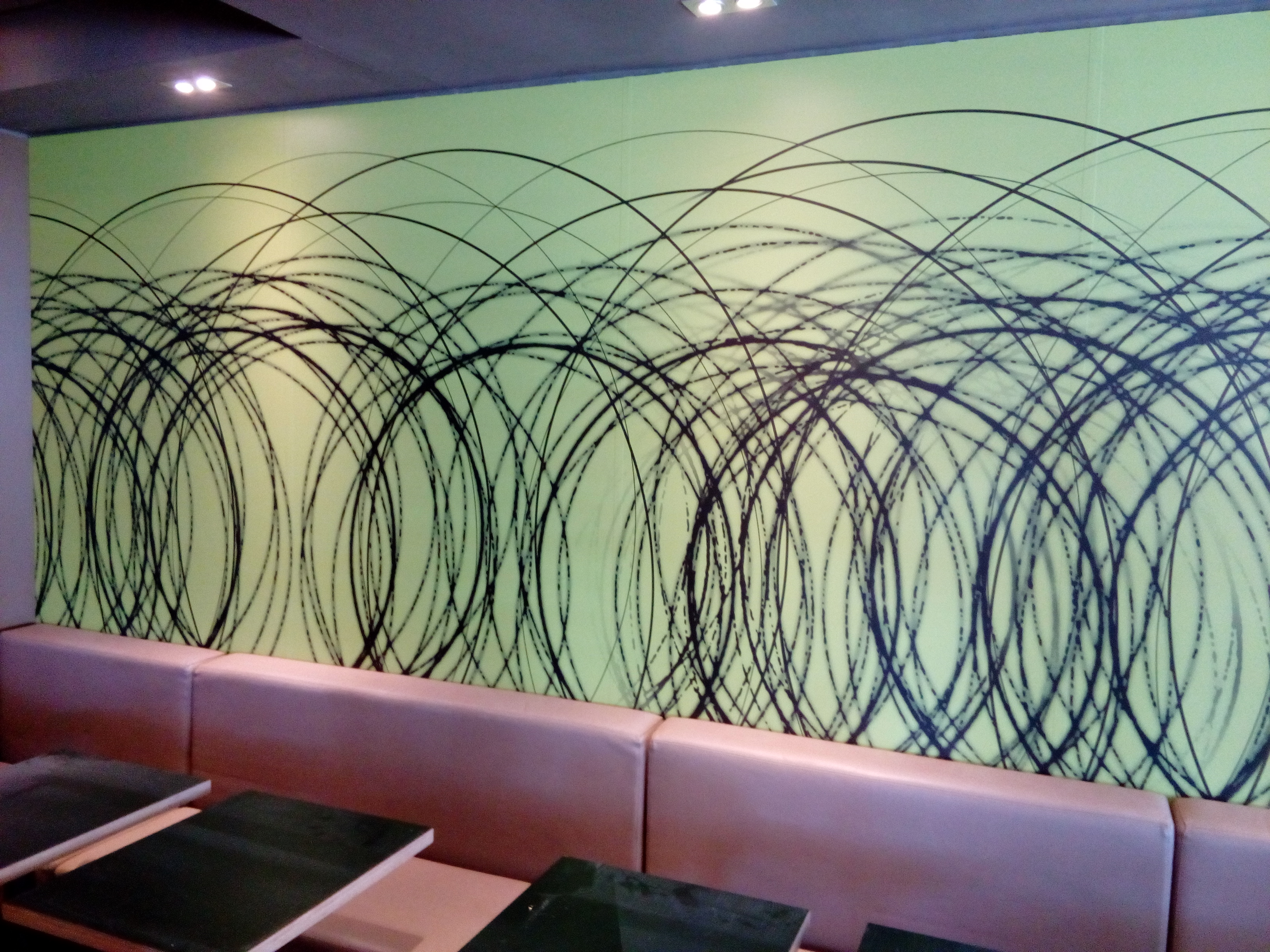 Mural geométrico con círculos abstractos en verde en el interior de un McDonald's