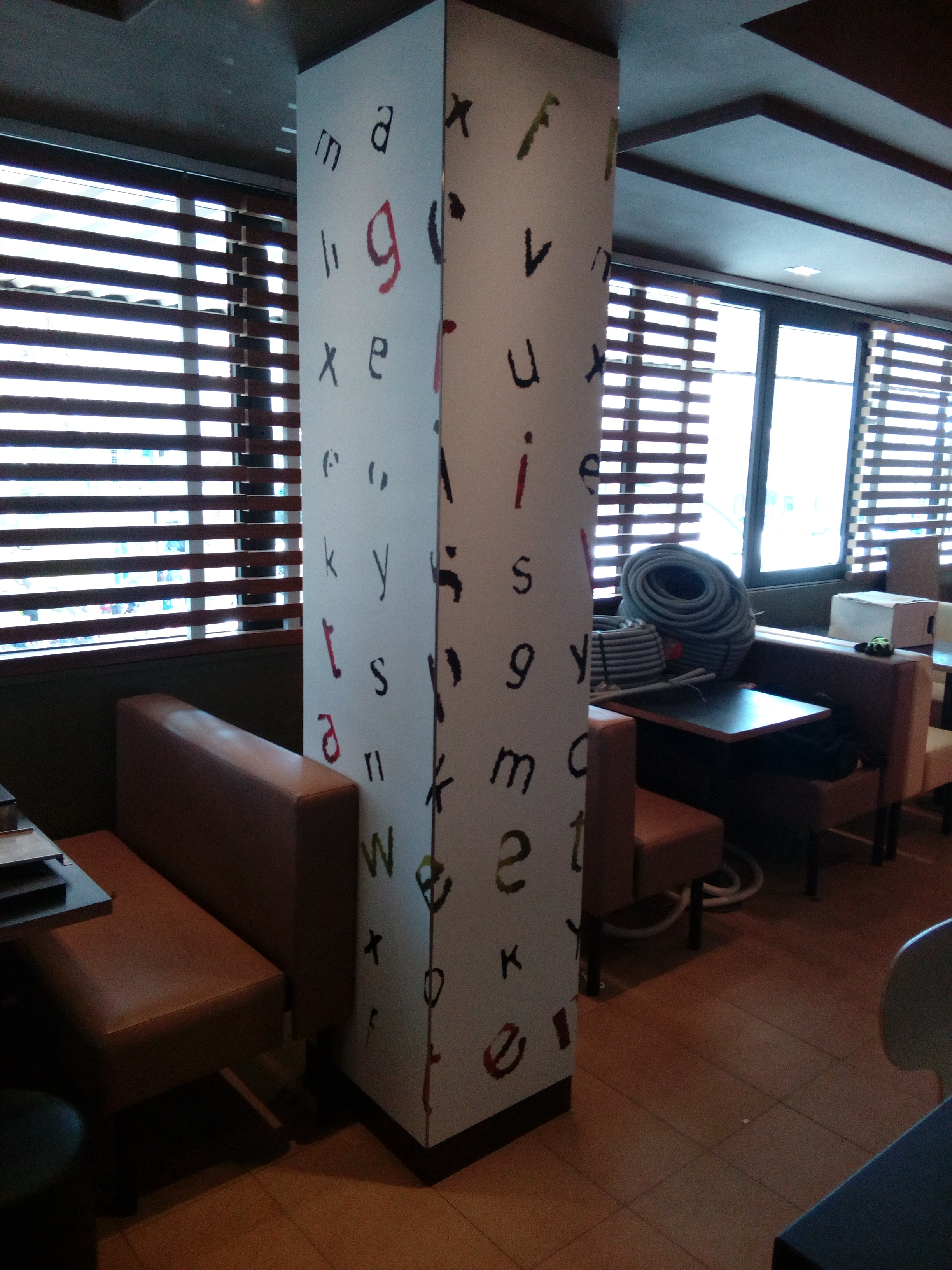 Columna decorada con patrón de letras de colores en restaurante McDonald's