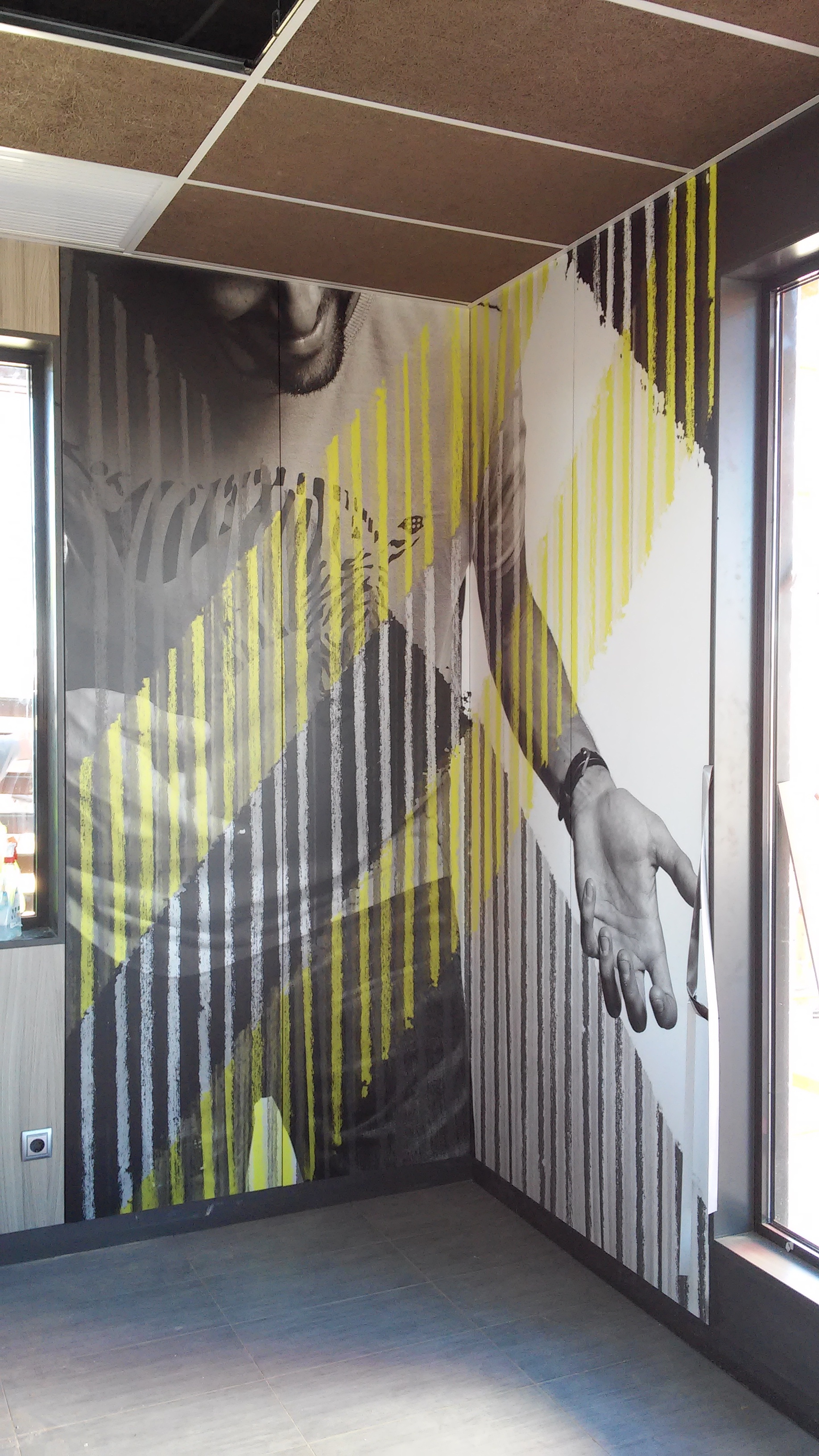 Instalación de mural artístico de retrato en tono amarillo en restaurante McDonald's