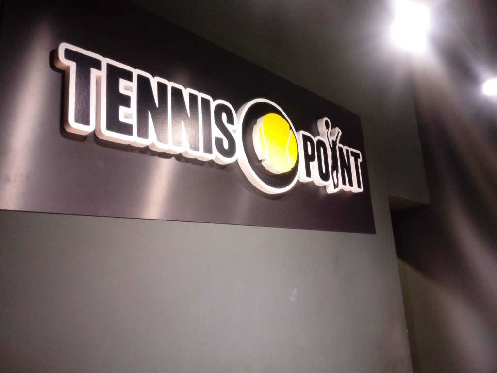 Detalle nocturno de logotipo Tennis Point iluminado en rótulo exterior
