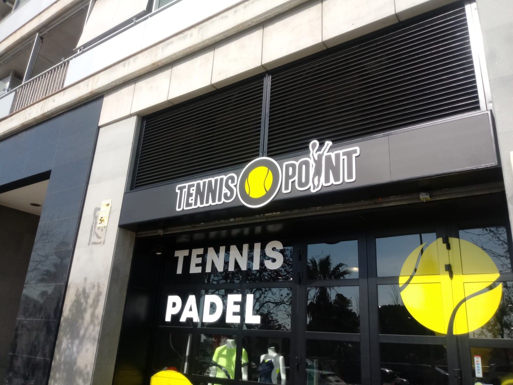 Fachada de tienda Tennis Point con rótulo exterior corporativo iluminado