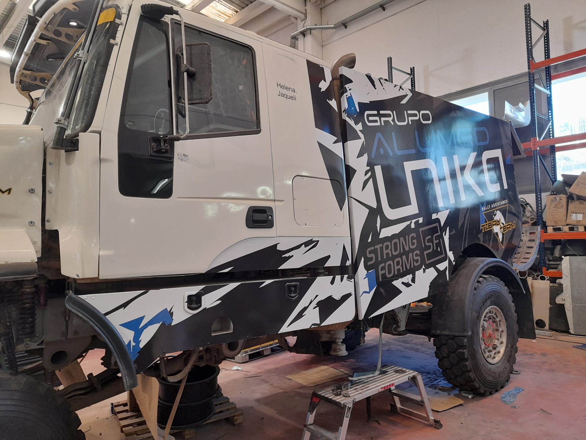 Vista trasera lateral camión Tibau Team Rally Assistance con diseño angular negro y azul