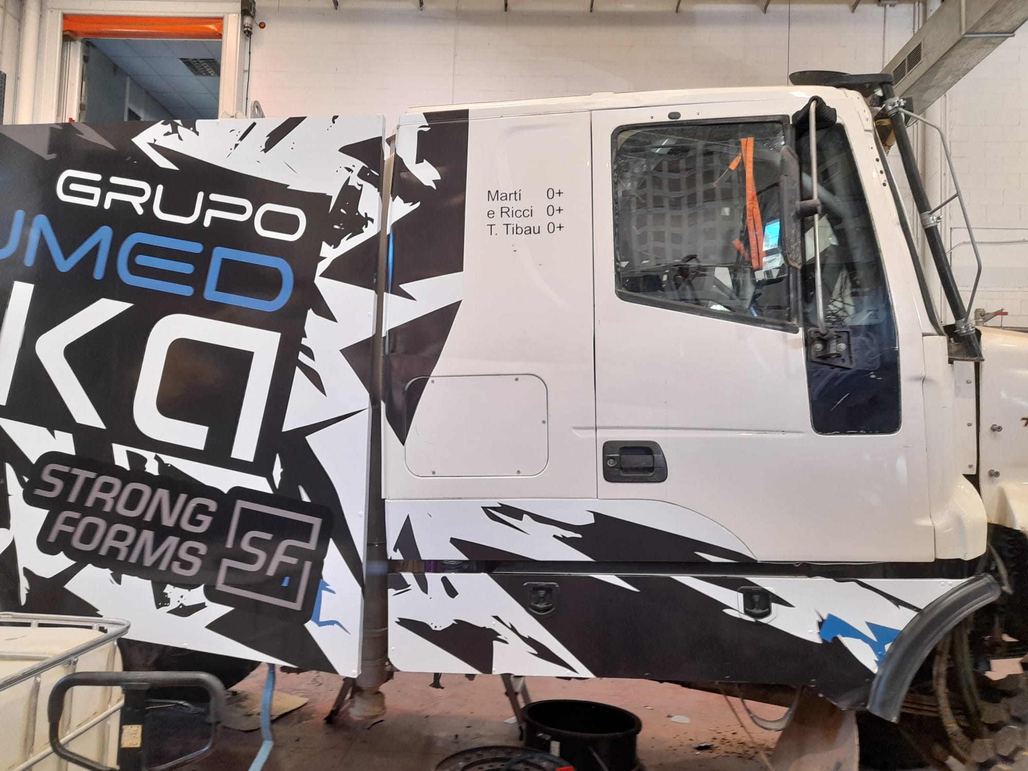 Detalle frontal del vinilado de cabina Tibau Team con gráfica de competición negro y blanco