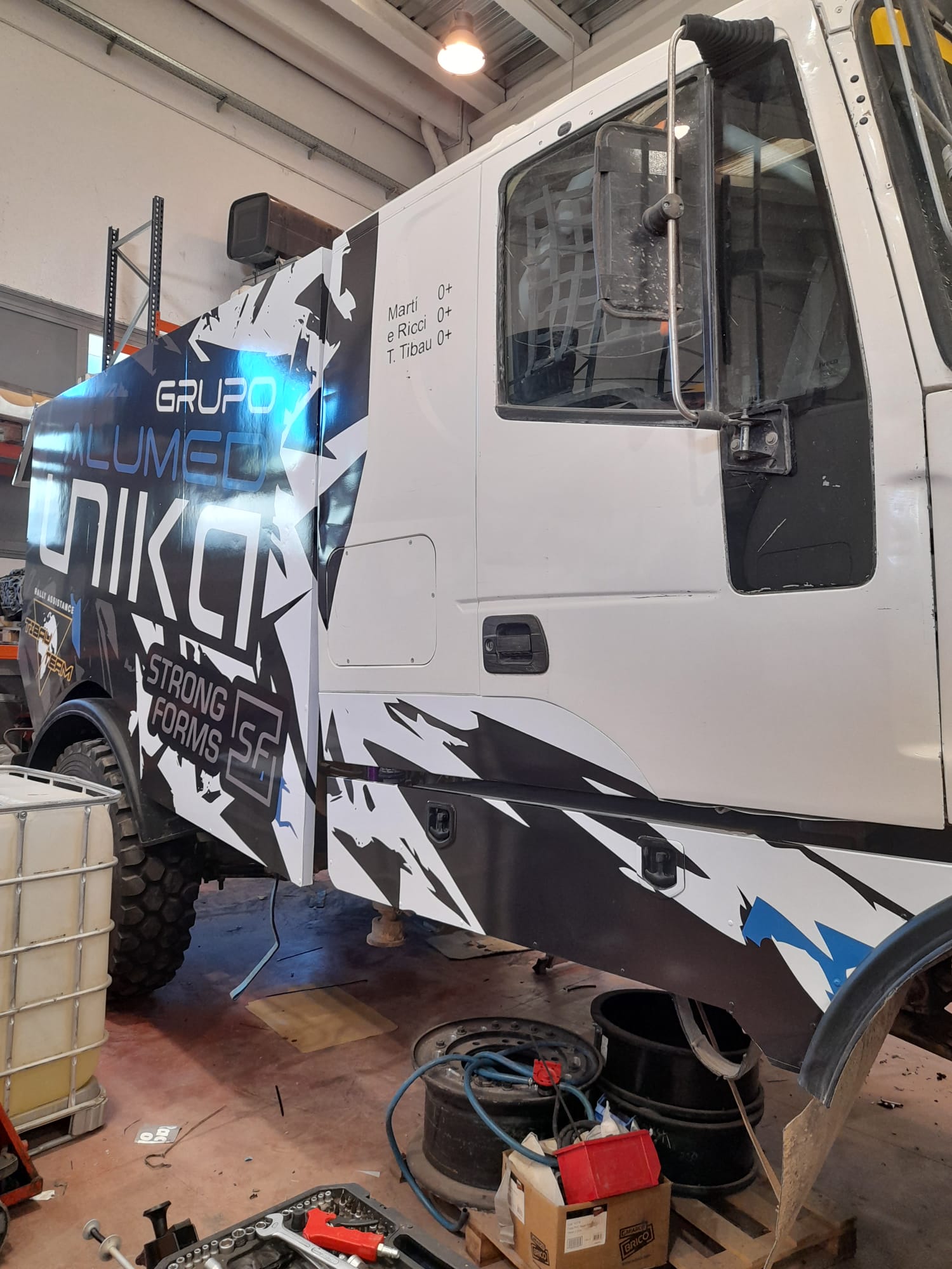 Camión de asistencia Tibau Team con wrapping completo en diseño angular negro blanco y azul por Unical Graphic