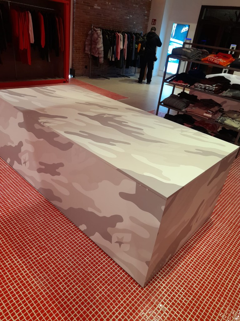 Detalle lateral de mesa retail Cold Culture con vinilado camuflaje personalizado