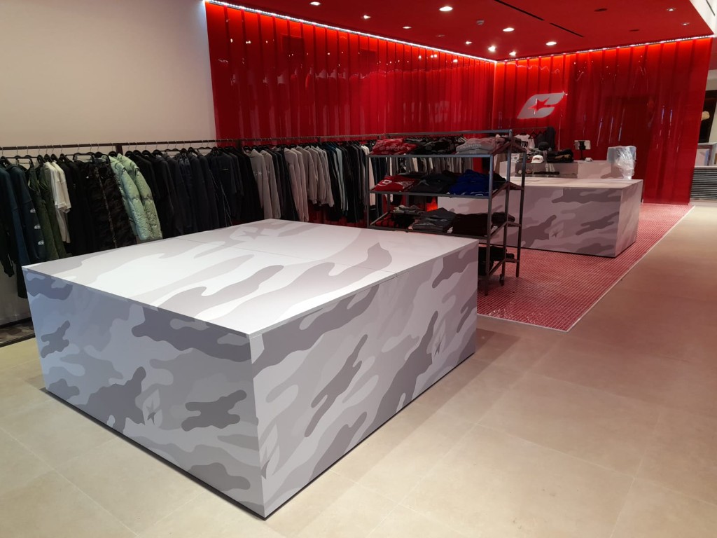 Perspectiva general del espacio retail con mobiliario personalizado y lineales de moda