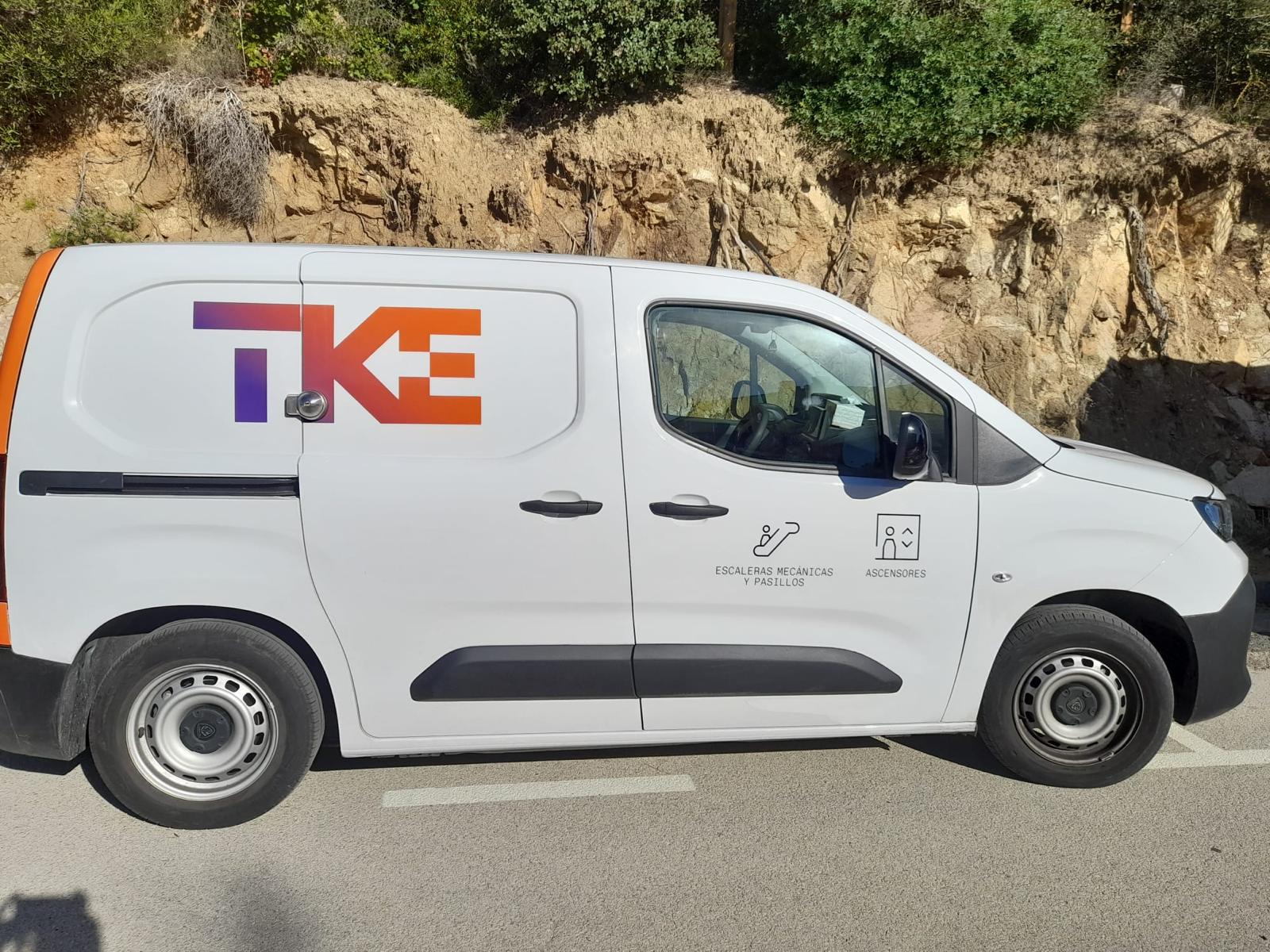 Vista lateral furgoneta TKE con logotipo corporativo en gran formato sobre fondo blanco