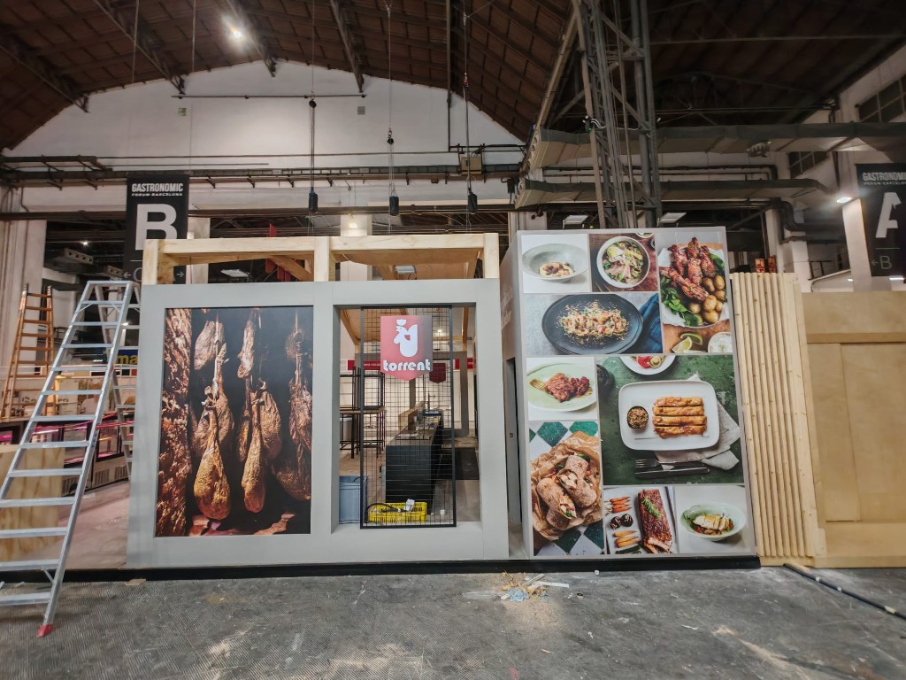 Panel lateral del stand con imágenes de producto y acceso principal Torrent