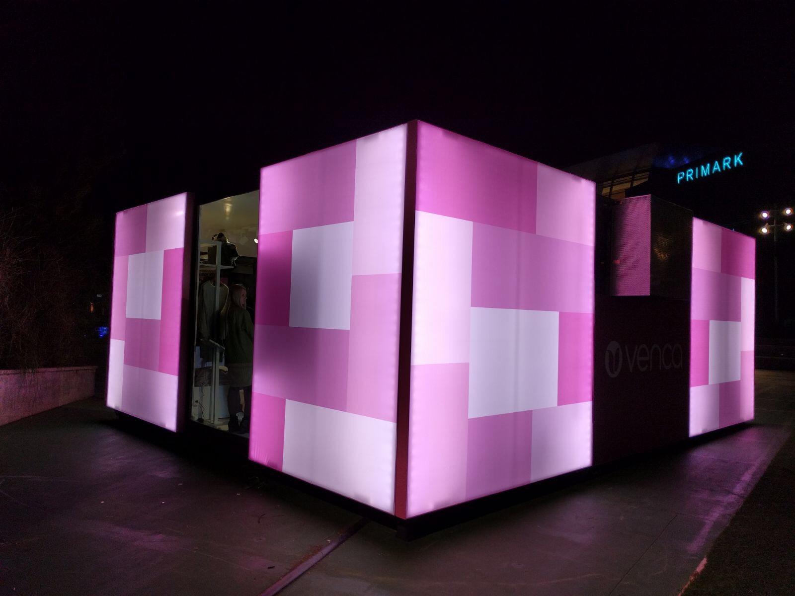 Pop-up store Venca vista esquina nocturna con paneles luminosos